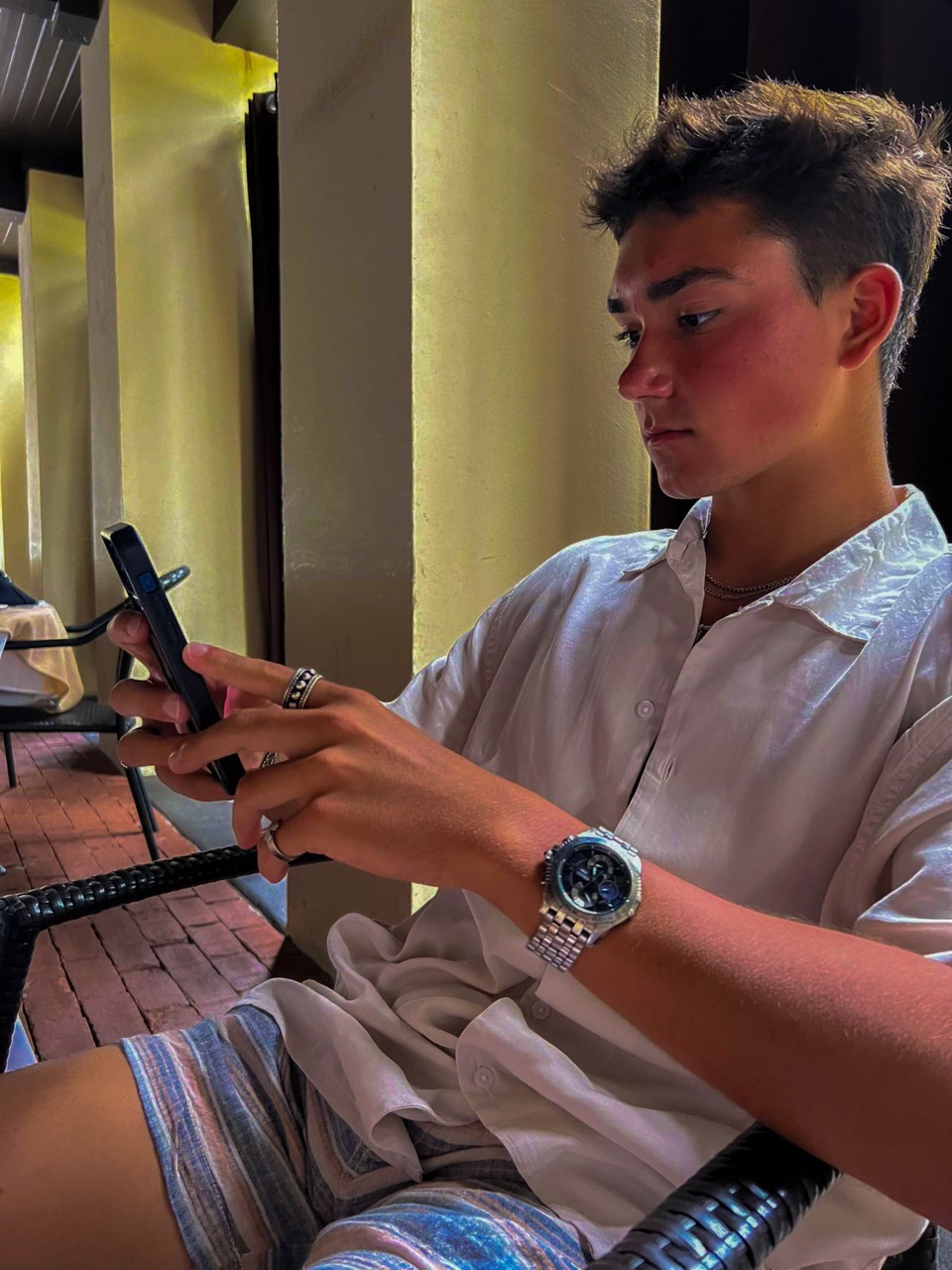Alex John Lukaszczyk seated and looking at his phone